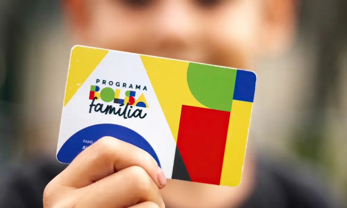 pessoa sozinha segurando o cartão do bolsa família