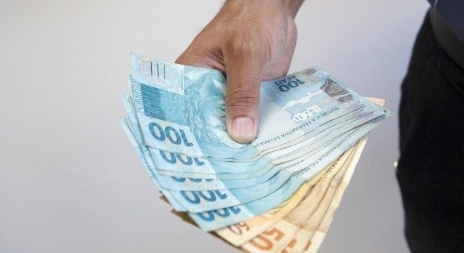 homem segurando notas de cem e cinquenta reais