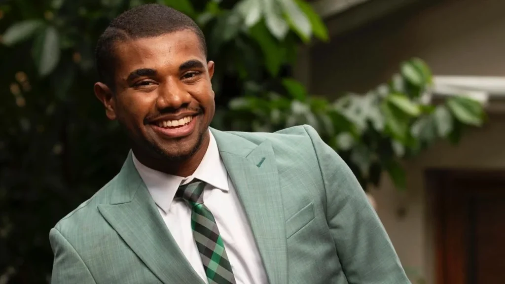 davi brito ex-bbb sorrindo e vestido de terno verde musgo