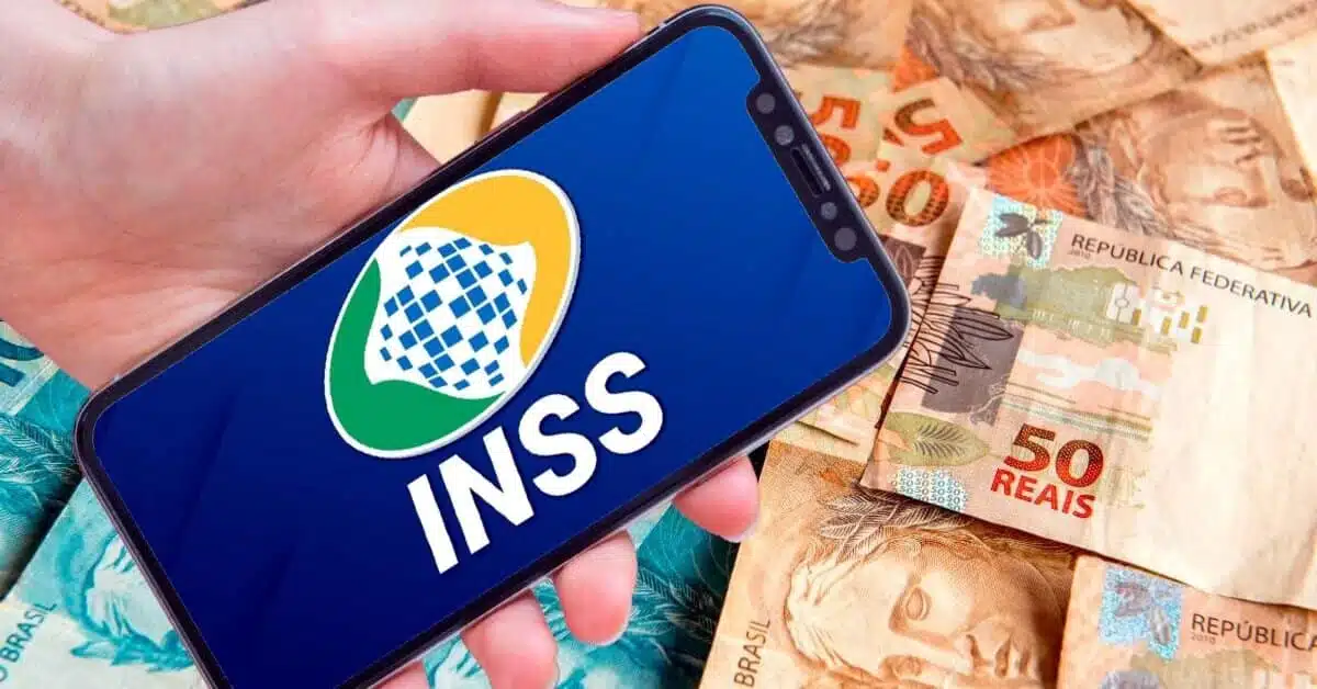 celular aberto no site do inss ao lado do pagamento feito com notas de 100 e 50 reais